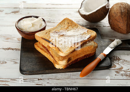 Tasty toasted bread with coconut oil on wooden background Stock Photo