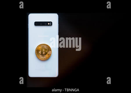 Smart Phone with a Physical Bitcoin on top Stock Photo