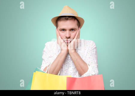 Bored european man leaning on palm. holding packets after shopping Stock Photo