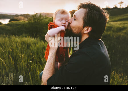 Father kissing infant baby outdoor Fathers day holiday happy family lifestyle dad and daughter child walking together summer vacations parenthood conc Stock Photo