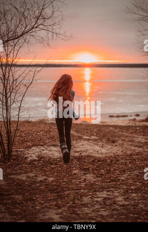 Woman enjoying time relaxing by the beautiful lake at sunrise. Stock Photo