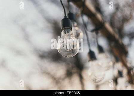 light bulbs in the street in daylight. A garland of light bulbs on a wooden pedestal in the afternoon in the sun Stock Photo