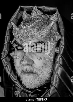 Man with thorns or warts, face covered with glitters. Senior man with white beard dressed like monster. Alien, demon, sorcerer makeup. Fantasy concept Stock Photo