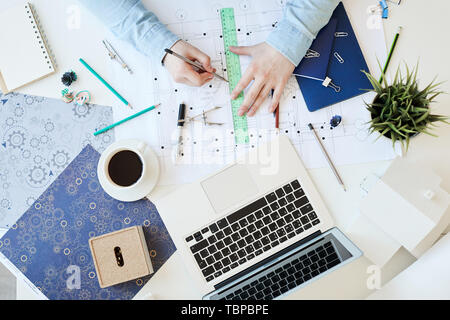 Directly above view of unrecognizable creative designer of house using pencil and ruler while drawing on blueprint of flat plan Stock Photo