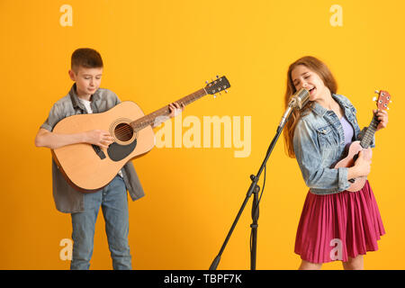 Teenage musicians playing against color background Stock Photo