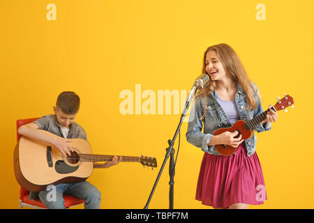 Teenage musicians playing against color background Stock Photo