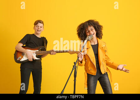 Teenage musicians playing against color background Stock Photo