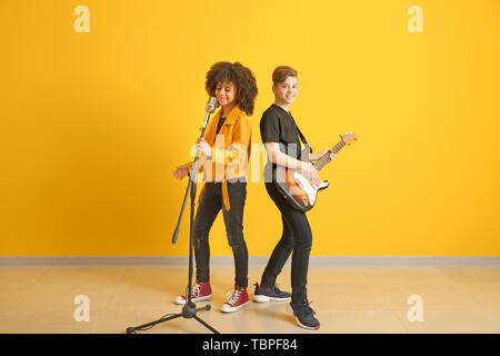 Teenage musicians playing against color wall Stock Photo