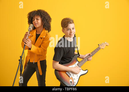 Teenage musicians playing against color background Stock Photo