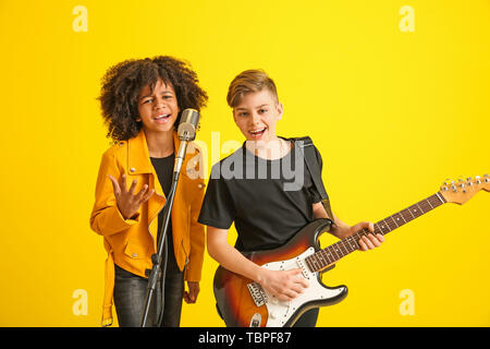 Teenage musicians playing against color background Stock Photo