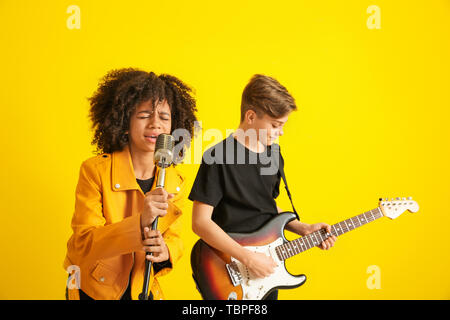 Teenage musicians playing against color background Stock Photo