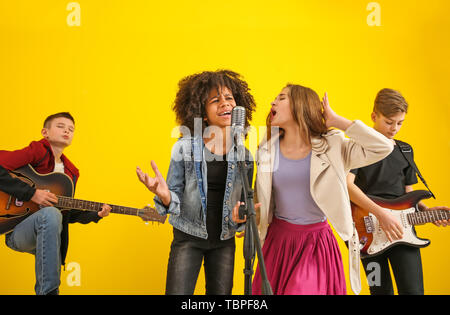 Teenage musicians playing against color background Stock Photo