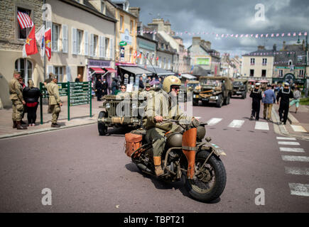 03 June 2019, France (France), Sainte Mere Eglise: In historical US uniforms, participants drive through the town of Sainte Mere Eglise on their vehicles from the Second World War. On 06.06.1944 about 14000 allied paratroopers of the US 82nd Airborne Division landed here in the course of Operation Overlord. 06.06.2019 is the 75th anniversary of the landing of allied troops in Normandy (D-Day). Photo: Kay Nietfeld/dpa Stock Photo