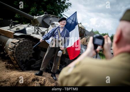 03 June 2019, France (France), Sainte Mere Eglise: A boy with the French flag has himself photographed in front of a historic US tank at Camp Gironimo. On 06.06.1944 about 14000 allied paratroopers of the US 82nd Airborne Division landed here in the course of Operation Overlord. 06.06.2019 is the 75th anniversary of the landing of allied troops in Normandy (D-Day). Photo: Kay Nietfeld/dpa Stock Photo