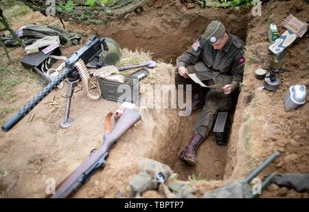 03 June 2019, France (France), Sainte Mere Eglise: An actor in historical US uniform sits in a trench in Camp Gironimo. On 06.06.1944 about 14000 allied paratroopers of the US 82nd Airborne Division landed here in the course of Operation Overlord. 06.06.2019 is the 75th anniversary of the landing of allied troops in Normandy (D-Day). Photo: Kay Nietfeld/dpa Stock Photo