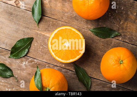 Fresh oranges and leaves on wooden board background Stock Photo