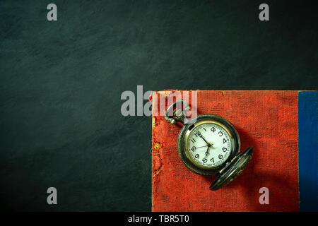 Pocket watch and old book on cement floor. Top view and copy space for text. Concept of time and education. Stock Photo