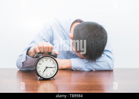 A tired young man holds the alarm clock Stock Photo