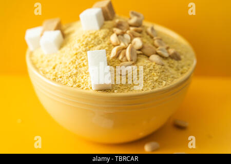 Bowl of Nigerian Yellow Garri in Yellow bowl with Peanuts and Sugar Stock Photo