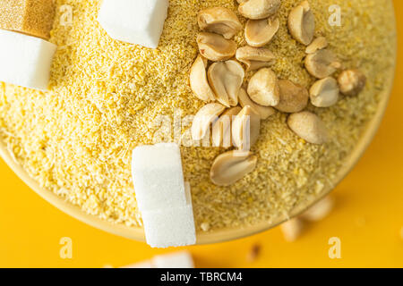 Bowl of Nigerian Yellow Garri in Yellow bowl with Peanuts and Sugar Stock Photo