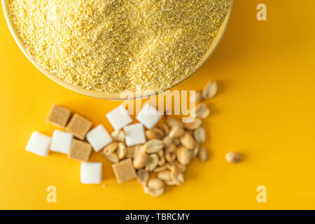 Bowl of Nigerian Yellow Garri in Yellow bowl with Peanuts and Sugar Stock Photo