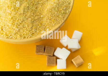 Bowl of Nigerian Yellow Garri in Yellow bowl with Peanuts and Sugar Stock Photo