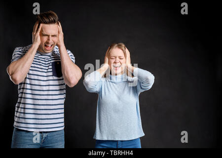 Young quarrelling couple on dark background Stock Photo