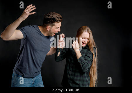 Young quarrelling couple on dark background Stock Photo