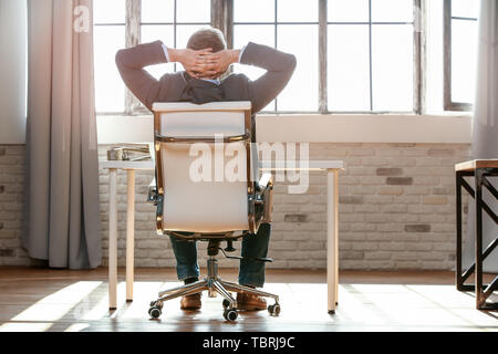 Handsome mature businessman having break in office Stock Photo