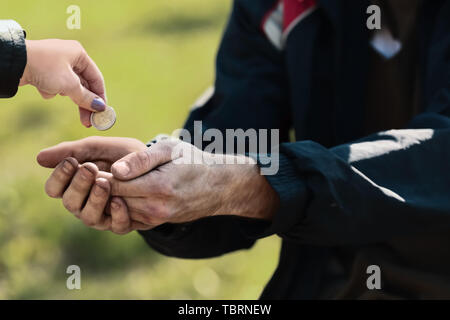 Woman giving money to poor homeless man outdoors Stock Photo