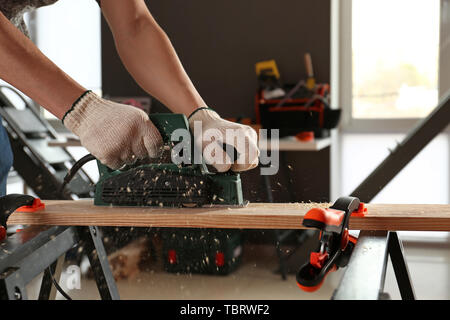 Male carpenter using electric planer in workshop Stock Photo