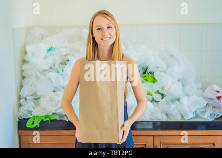 Woman holding paper bag amid a pile of plastic bags. Zero waste concept. The concept of World Environment Day Stock Photo