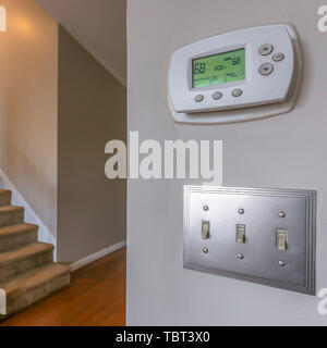 Square frame Air conditioning control panel and light switches mounted on a white wall Stock Photo