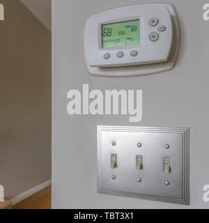 Square Wall mounted air conditioner unlit control and light switches inside a house Stock Photo