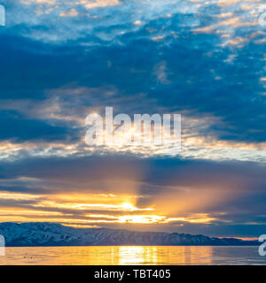 Square frame Golden sun shining through the cloudy sky and reflected on the shiny lake below Stock Photo