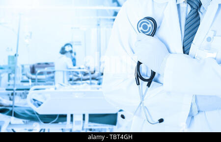 Asian doctor holding stethoscope on blurred nurse nursing patient in hospital room use us hospital background