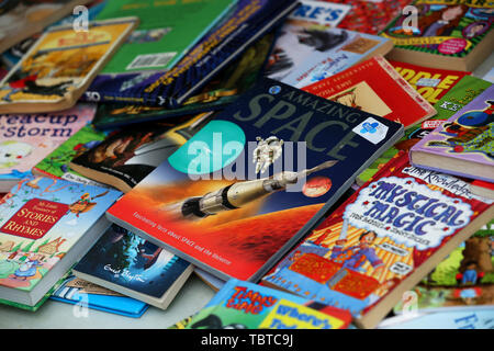 Pile of children's books for sale on a charity stall in Sussex, UK. Stock Photo