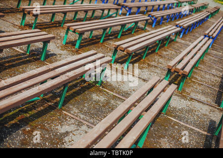 Diagonal rows of old empty brown wooden benches Stock Photo