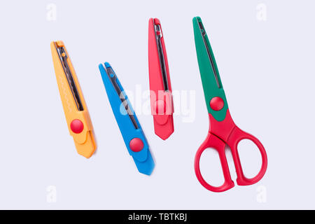 Colored stationery knives and scissors. Colorful stationery objects isolated on white background. Stock Photo