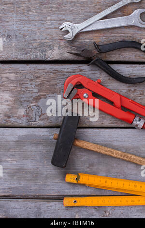 Wood background with various tools. Hammer, folding ruler, adjustable wrench, pliers and spanners. Space for text. House repairing theme. Stock Photo