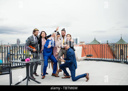 A group of joyful businesspeople having a party outdoors on roof terrace in city. Stock Photo