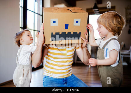 Two toddler children with father playing indoors at home. Stock Photo