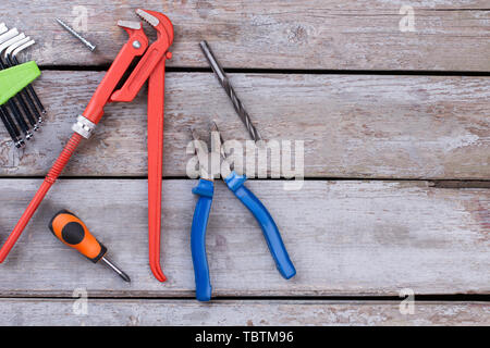 Different construction tools on the wooden background. Adjustable wrench, screwdriver, pliers and Allen keys. Space for text. Stock Photo