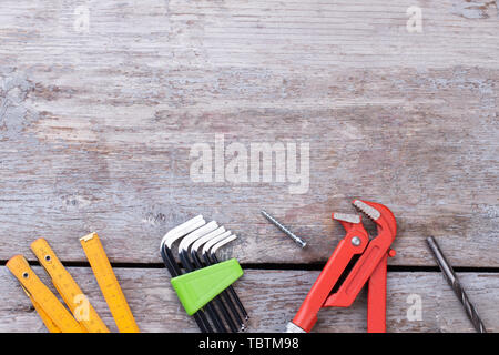 Various tools for construction on wooden background. Folding ruler, set of Allen keys, adjustable wrench and drill bit. Space for text. Stock Photo