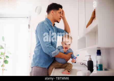 Father and small toddler son in a bathroom indoors at home, washing. Stock Photo