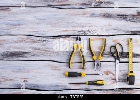 Construction tools on wooden background with copy space. Pliers, screwdrivers, scissors and builders tape measure. Space for text. Stock Photo