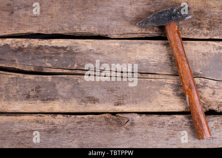 Old hammer on rustic wooden boards. Tool on old cracked wooden floor. Space for text. Stock Photo