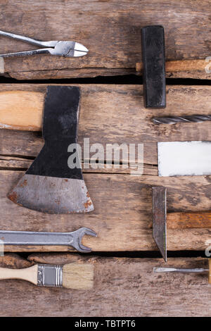 Old wooden board with various building instruments. Set of tools including pliers, axe, hammer, wrenches, paintbrush and palette-knife. Stock Photo