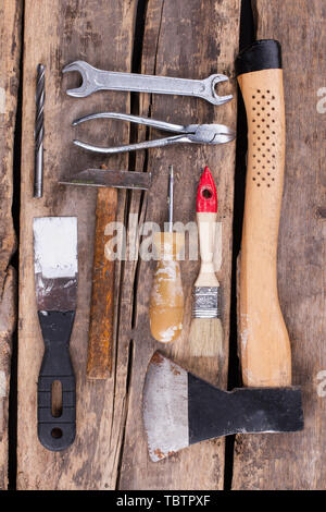 Old rusty tools on a wooden boards background. Variety of hand tools for construction on rustic background, top view. Stock Photo