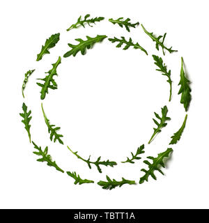 Pattern from arugula in round circle frame isolated. Circle shape in fresh green ruccola or arugula. Isolated on white with clipping path. Top view or flat lay. Can use for design vegan concept Stock Photo